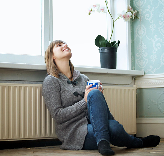 A woman sitting on the floor holding a cup.